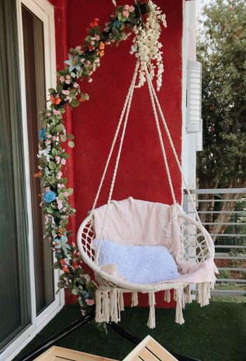 another reviewer's swing hanging in their yard, with a blanket and pillow on it 
