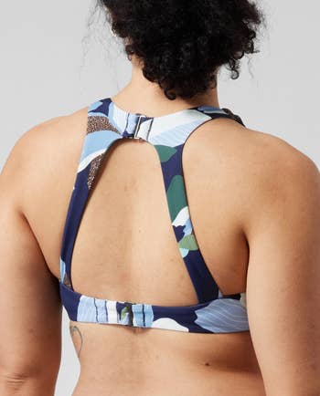 the back view of a model wearing the same bikini top in a blue and green floral print 