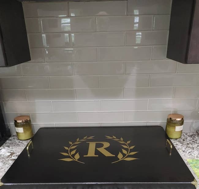 Stove with a black stove cover, gold handles and an 'R' with leaves in the center
