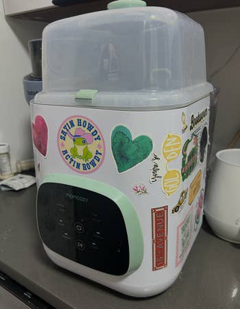 Baby vessel sterilizer connected a room counter, decorated with assorted colorful stickers, including hearts and cartoon graphics