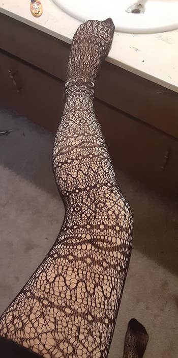a reviewer wearing the khaki leggings underneath a pair of fishnet stockings 
