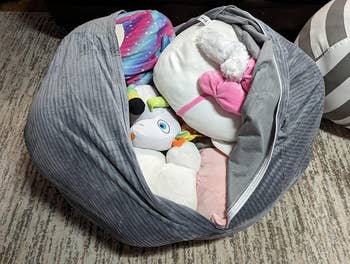 grey corduroy bean bag open to reveal the stuffed animals inside