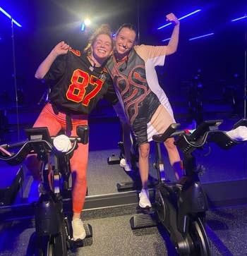 Two spin instructors, one in a Travis Kelce jersey and the other in the shirt designed to look like the reputation catsuit
