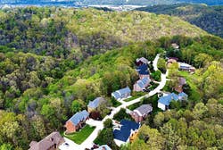 Reviewer drone footage of several houses surrounded by forests