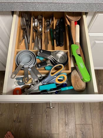 on left, reviewer pic of messy cluttered kitchen drawer with various utensils, measuring cups, and scissors