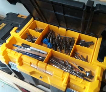 close up of different reviewer's open box, revealing a divided tray of different drill bits, pens, and other supplies