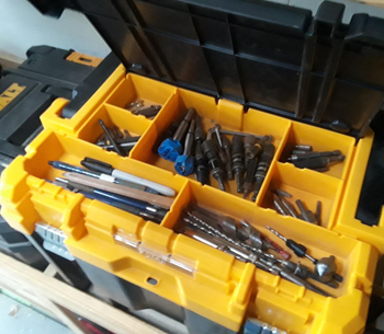 close up of different reviewer's open box, revealing a divided tray of different drill bits, pens, and other supplies