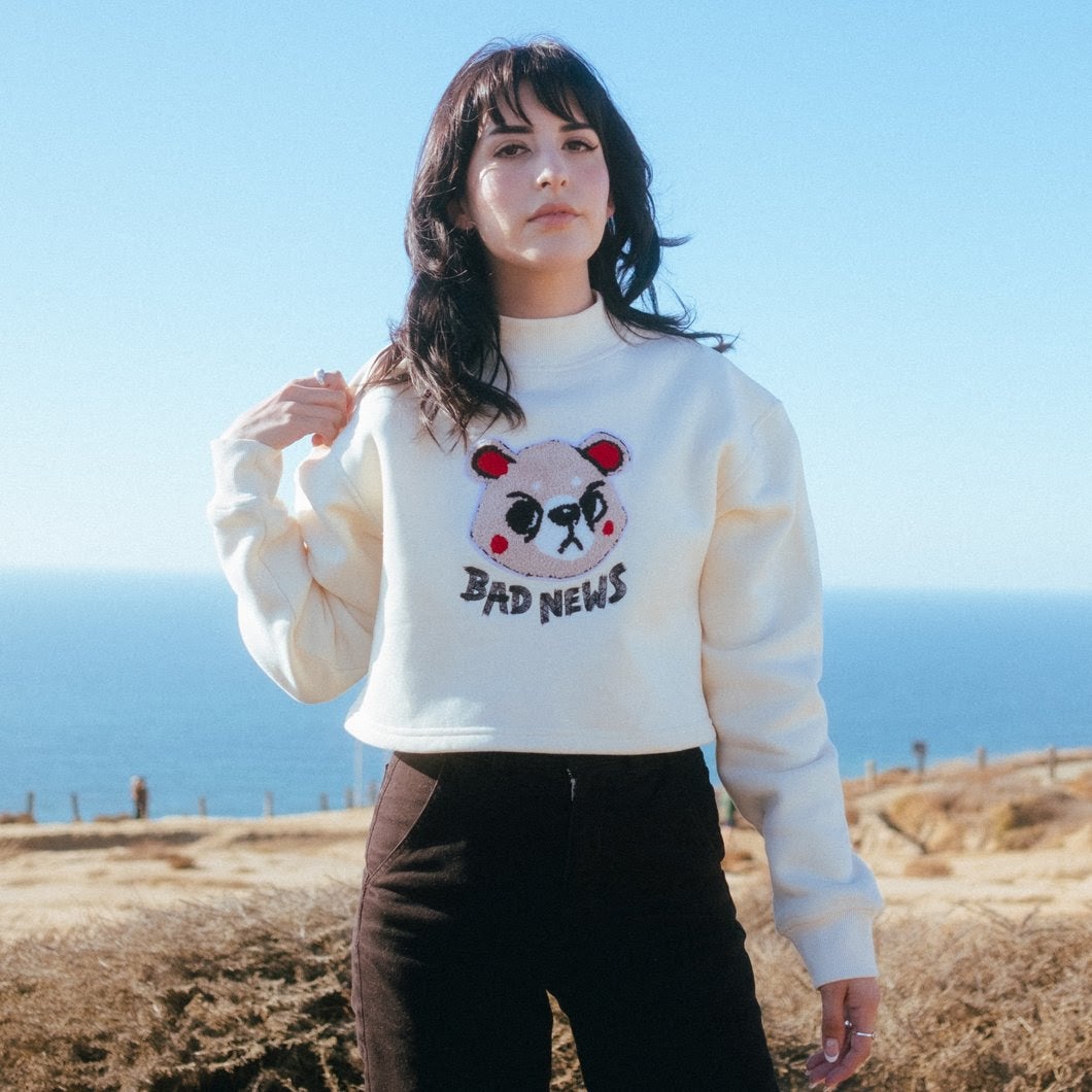 model in a cropped mockneck sweatshirt with an illustrated angry pink bear on it that says