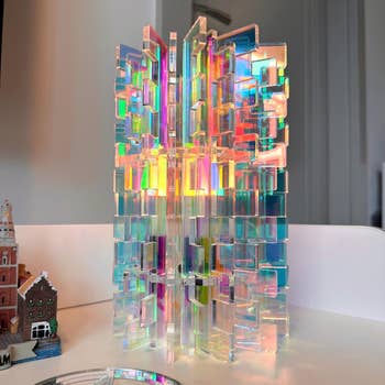 Intricate, reflective acrylic sculpture with geometric patterns; holographic quality  casts colorful airy  reflections connected  surrounding surfaces