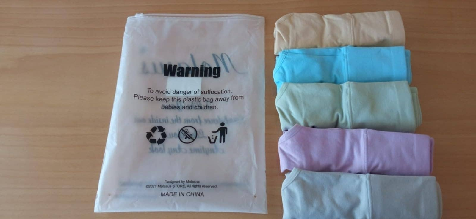 reviewer showing five rolled up pairs of underwear next to bag they came in