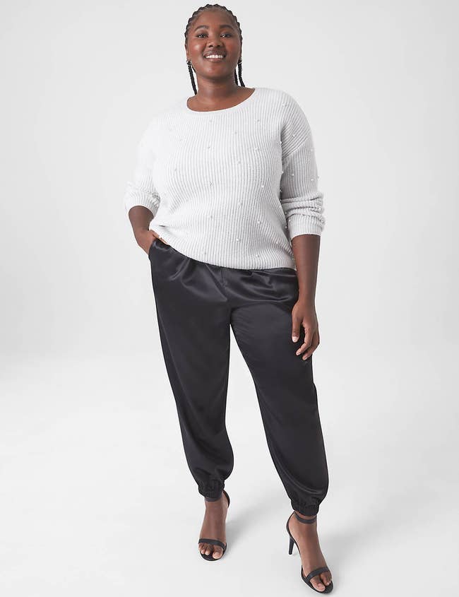 model wearing the black satin joggers with a white sweater and black heels