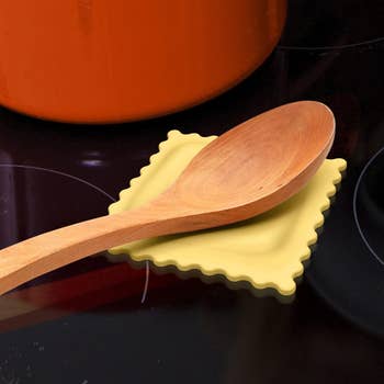 Wooden spoon resting on a yellow ravioli silicone spoon rest