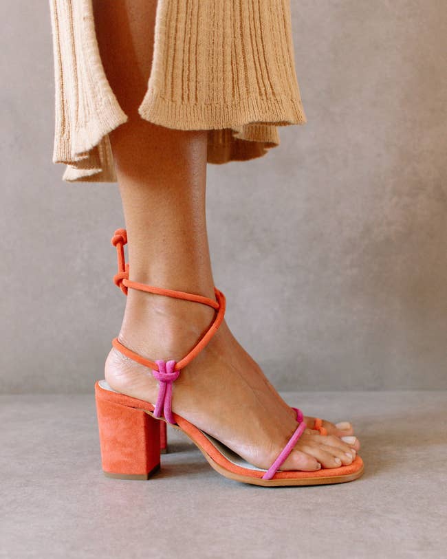 a model poses in the orange and pink heels