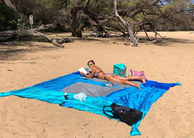 reviewer at the beach laying on large blue beach blanket