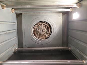 Interior of an oven with racks and a fan at the back