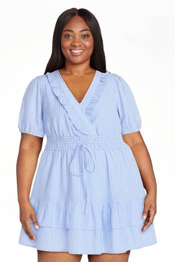 Person wearing a stylish, short ruffled wrap dress, smiling confidently