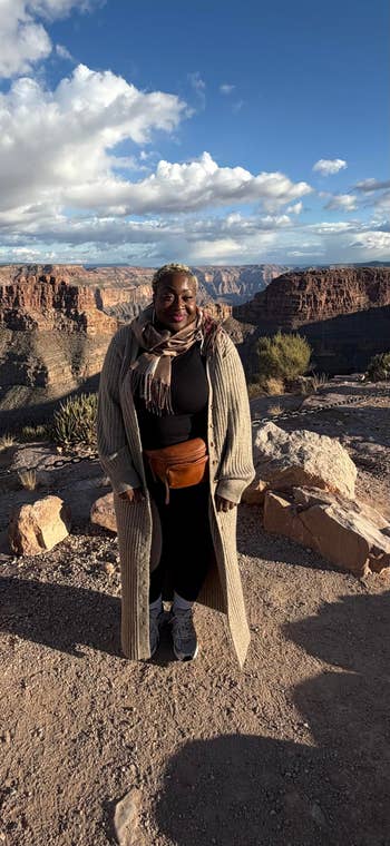 Person successful  long, textured overgarment  with scarf, lasting  connected  a rocky cliff with a immense   canyon view. Casual outdoor fashion