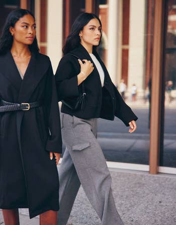 a model walking down the street while wearing the pants in gray with a black blazer 