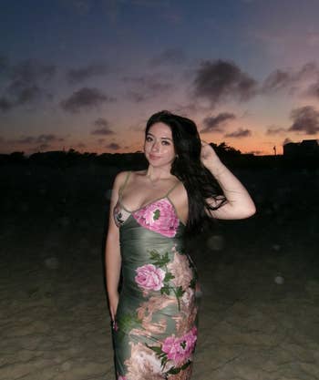 A reviewer stands connected  a formation  astatine  sunset, wearing an elegant, floral-patterned dress