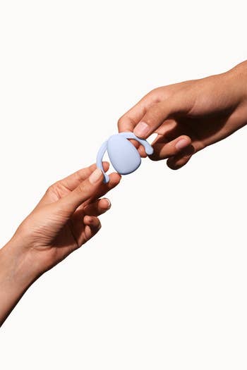 Hands holding light blue vibrator by wings