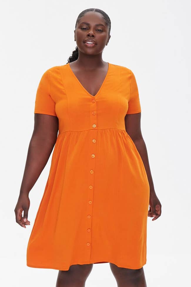 model in short-sleeve, knee-length, button-front orange dress