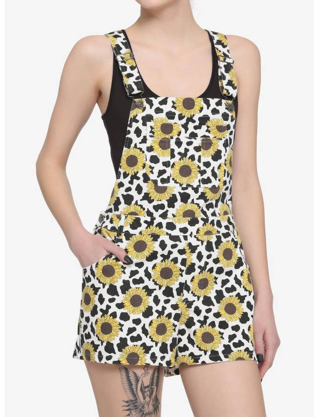model in the black and white cow print and yellow sunflower print short overalls