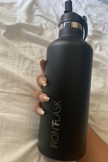reviewer holding their black water bottle