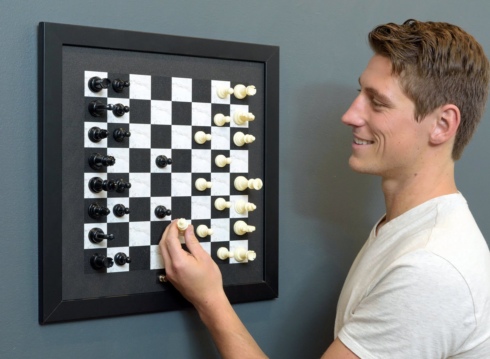 person playing chess with the wall-mounted chess board