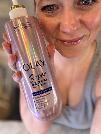 A idiosyncratic   smiling holds a vessel  of Olay Super Serum Body Wash, advertised for unsmooth  and bumpy skin, highlighting its skincare benefits