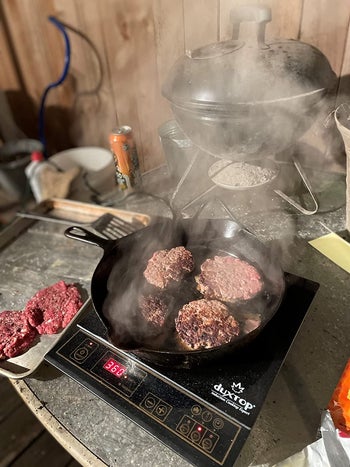 Reviewer using the burner outside to cook burgers