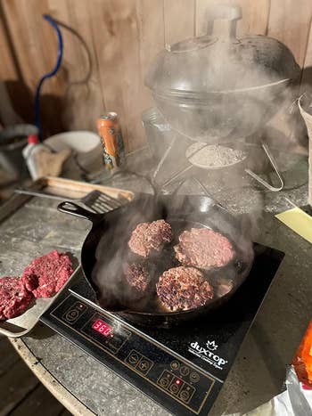 Reviewer using the burner outside to cook burgers
