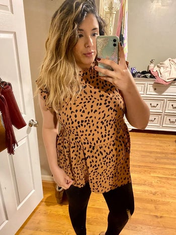 pregnant reviewer wearing light brown and black leopard sleeveless top with ruffle detail