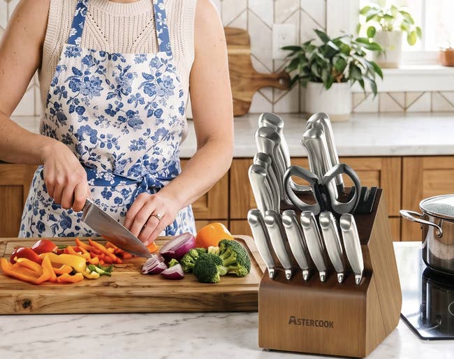 Person chopping vegetables with a weapon acceptable connected display; includes assorted knives and scissors successful a woody artifact connected a room counter