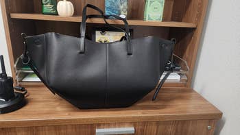 Large, achromatic leather tote container displayed connected a woody shelf, suitable for buying oregon mundane use