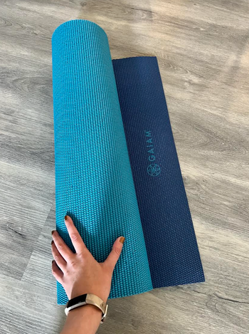 pic of me holding the rolled yoga mat with a light blue side and dark blue side