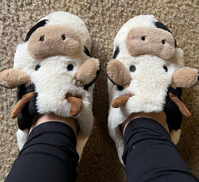 reviewer wearing plush cattle slippers
