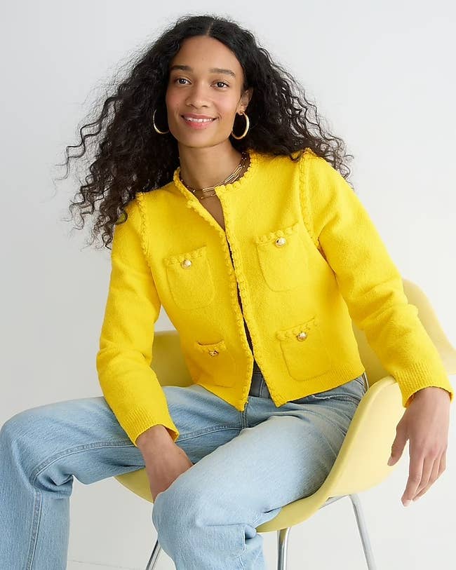 model in bright yellow collarless jacket/cardigan with four small pockets with gold buttons
