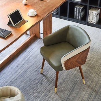 an green upholstered chair with wood herringbone siding at a desk with an iPad on it