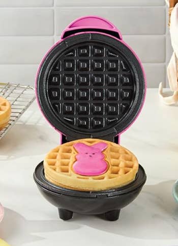 Waffle shaper  with a bunny-shaped waffle inside, surrounded by freshly made waffles connected  a room  counter