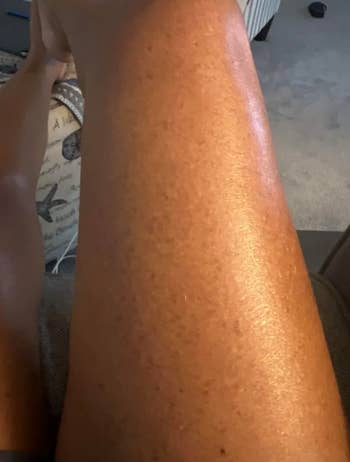 Close-up of a smooth, moisturized leg on a couch, suggesting skincare or beauty product usage