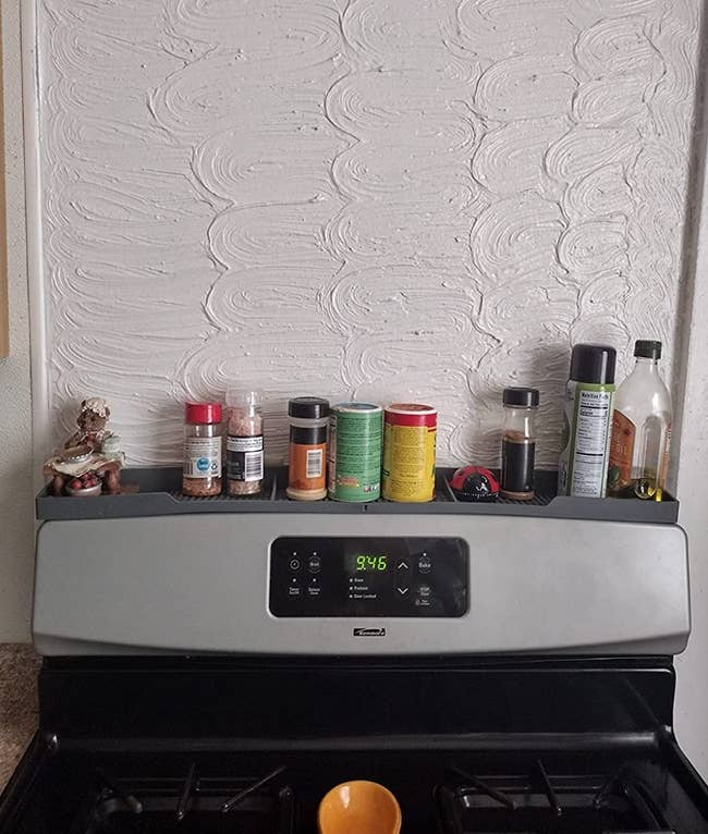 gray silicone shelf attachments on top of a stove holding seasonings 