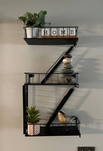 Wall-mounted support  with decorative plant, tiny  vertebrate  ornament, and stacked stones with inspirational words. 