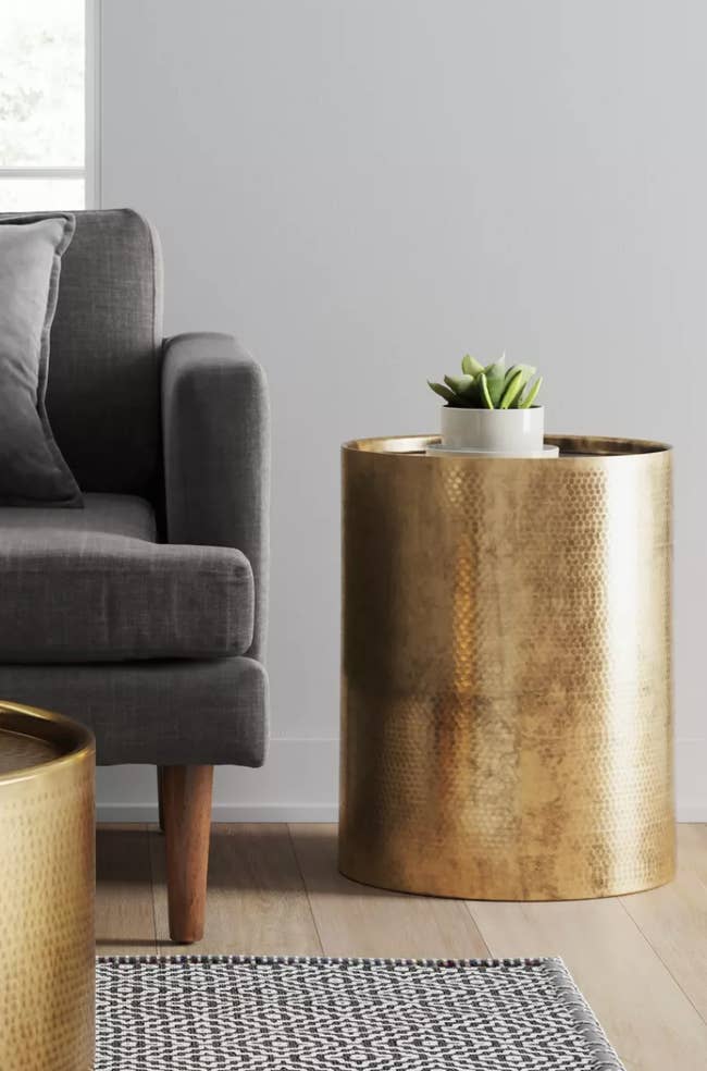 a gold side table next to a couch