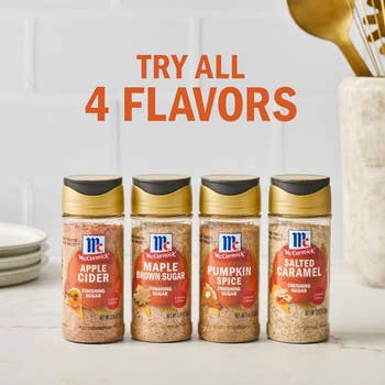 Four McCormick finishing sugar bottles in Apple Cider, Maple Brown Sugar, Pumpkin Spice, and Salted Caramel flavors are displayed on a kitchen counter