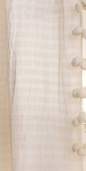 Sheer curtain with decorative pom-poms used for home interior