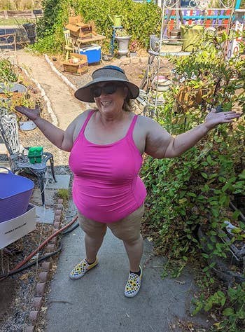 Woman in a garden wearing a wide-brimmed hat and the. swimsuit in pink 