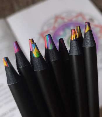 Set of multicolored pencils with intricate tips, displayed against an unfastened  coloring book