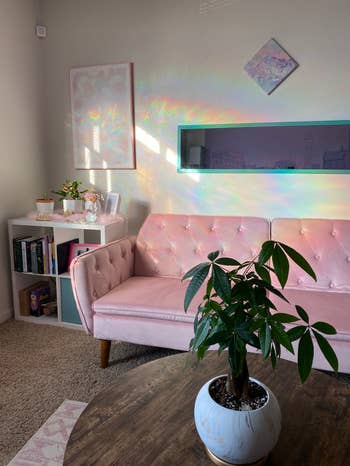 the pink futon in a reviewer's living room styled with an area rug and coffee table