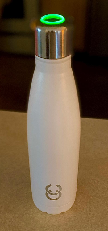a reviewer photo of a white water bottle with an illuminated silver cap on top 
