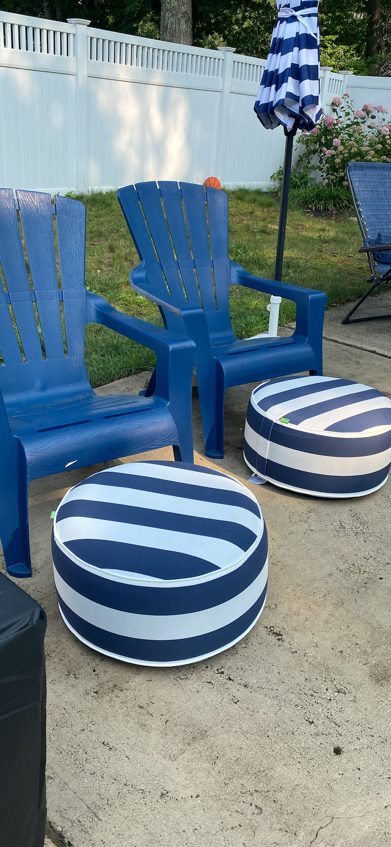 another reviewer photo of two navy and white striped inflatable ottomans in front of two patio chairs